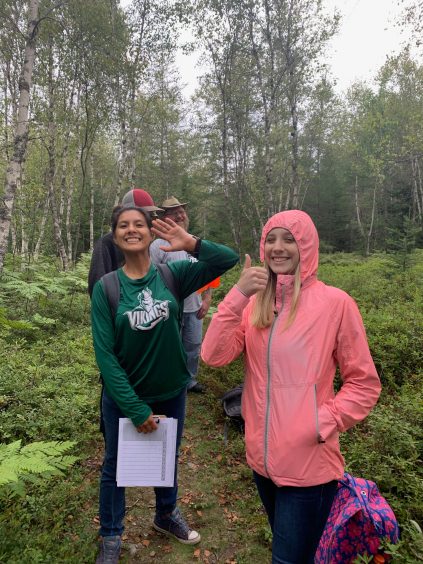 Students smiling and giving a thumbs up on a walk in the forest