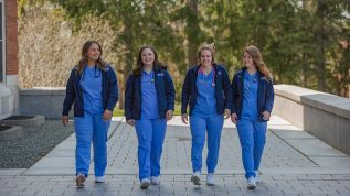 Four nursing students walking on campus
