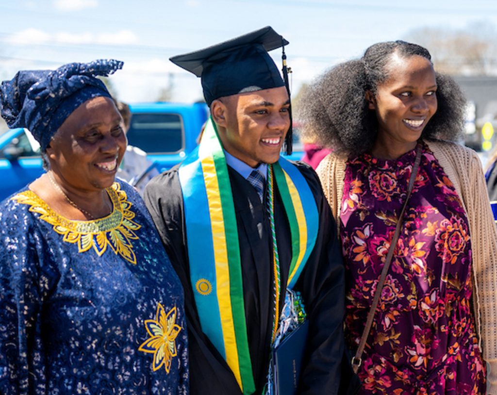 A student poses with 2 family members outside after graduation