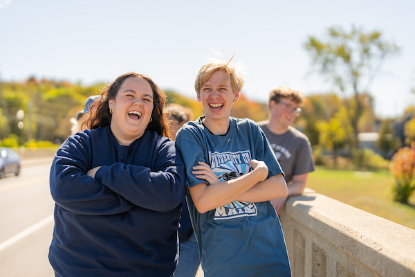 Two students leaning on each other and smiling