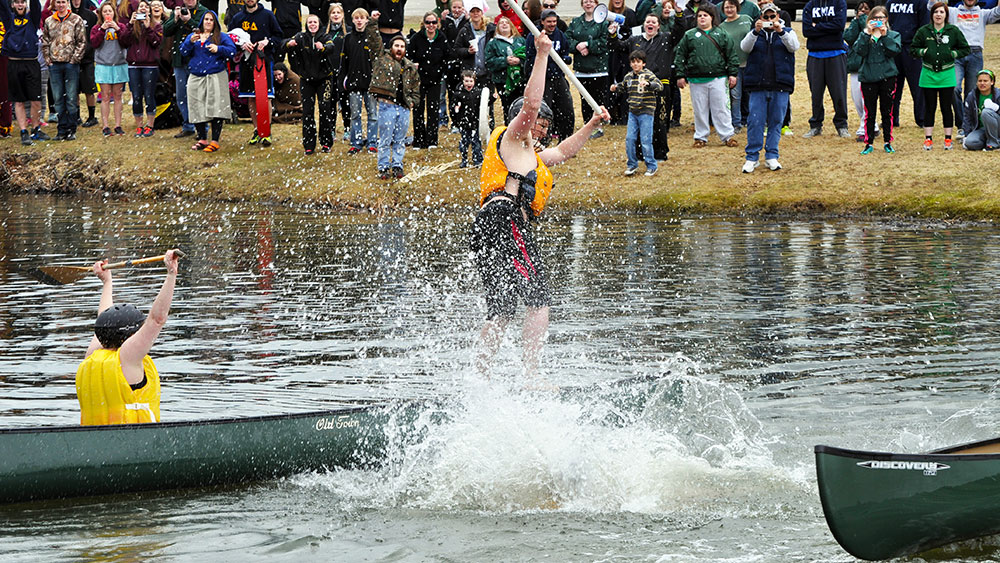 Crowd cheering from the shore of UMM pond during Greek Games