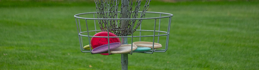 Metal disc golf basket in a grass field