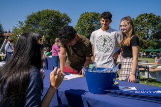 students outside at a table that contains UMaine Machias information