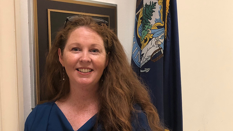 Rhiannon Hampson in front of the State of Maine flag