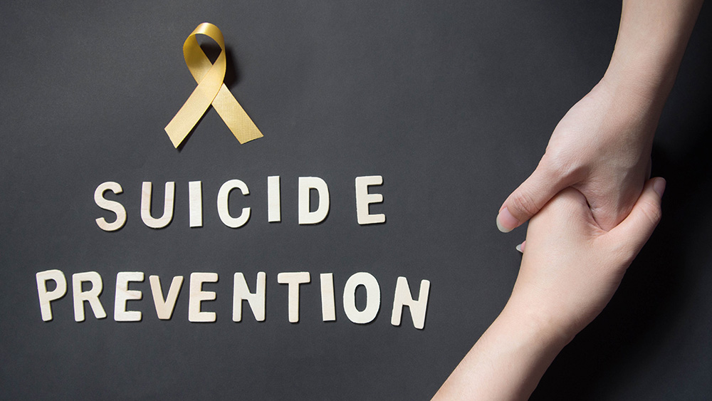 A yellow ribbon, the words "suicide prevention" and two hands grasping each other
