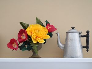 A paper flower bouqet next to a teapot