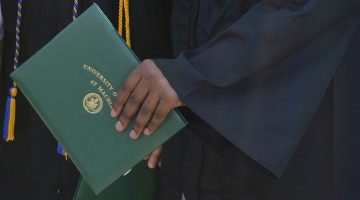 A close-up of someone's hand holding a diploma cover