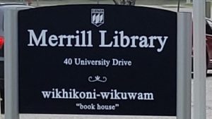 A blue signs says: Merrill Library 40 University Drive wikhioni-wikuwam "bookhouse"