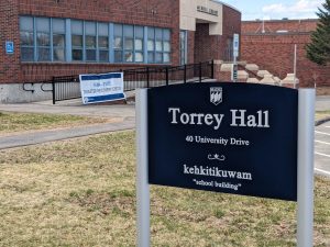 Torrey Hall sign outside with Merrill LIbrary and a FEMA banner in the background