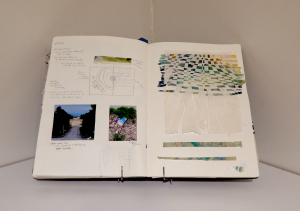 A sketchbook is opened to one of the pages with words and colored samples of ideas