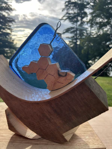 small potential model for the new sculpture. a wooden base with a diamond shaped piece of blue glass and a wooden honey comb in front of it. 