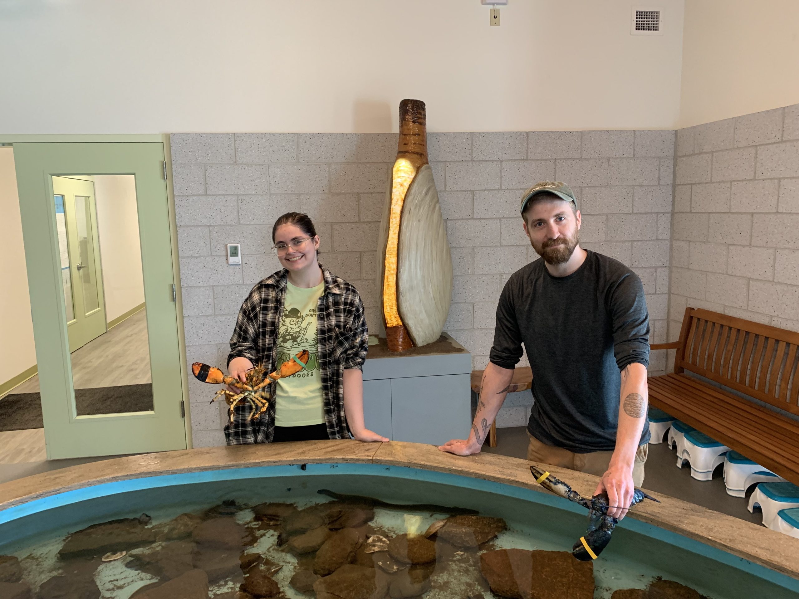 Students pose with lobsters by the touch tank at Downeast Institute