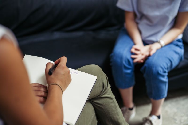 A shot showing the hands and legs of two people in a counseling session