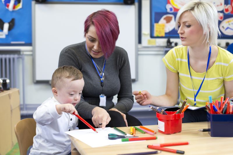 Two women in a classroom with a child who has down's syndrome