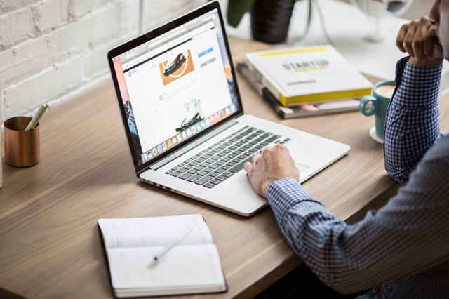 man sitting at a laptop with a notepad and coffee