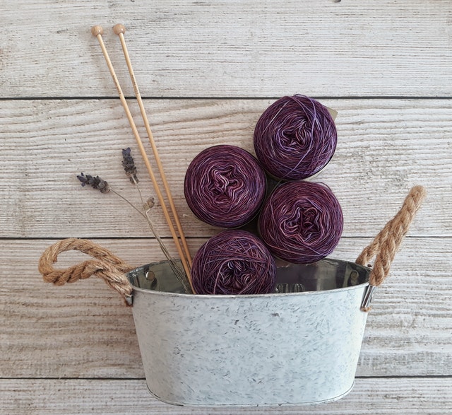 Bowl of purple yarn against a barn wood wall.