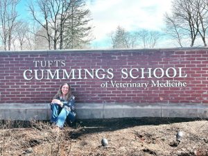 Morghan sits in front of a brick sign for Cummings School of Veterinary Medicine during her fist visit.