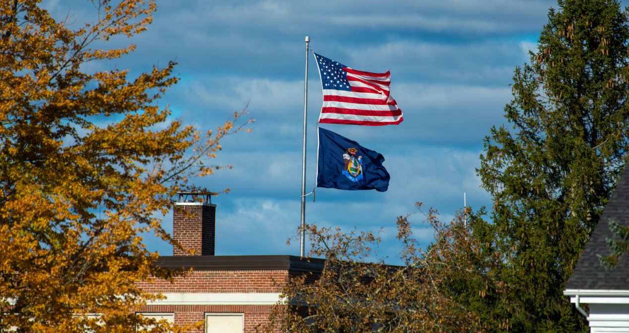 Photo of Powers Hall with Maine State flag and U.S. flag