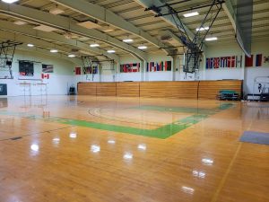 A sealed, wooden gym floor with wooden bleachers running along the side of the court.