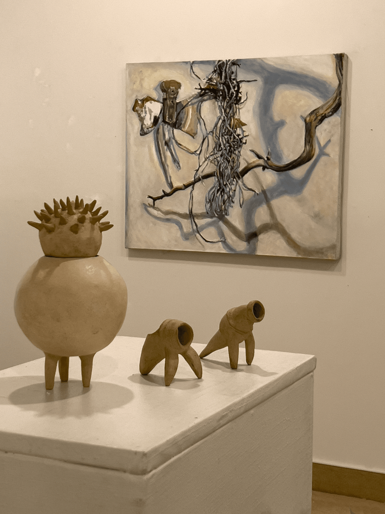 Three class statues on a pillar with an abstract painting in the background.